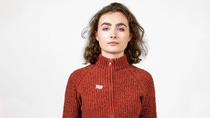 Frontalaufnahme einer jungen Frau, die eine Strickjacke mit Rollkragen trägt. Frontalaufnahme einer jungen Frau, die eine Strickjacke mit Rollkragen trägt.
