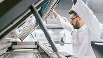 Ein Mitarbeiter steht vor einem großen 3D-Drucker und begutachtet das Ergebnis. Ein Mitarbeiter steht vor einem großen 3D-Drucker und begutachtet das Ergebnis.