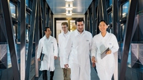 Three men and a woman in white working coats walking. Three men and a woman in white working coats walking.