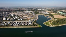 The picture shows an aerial view of a sprawling industrial and port landscape on a large river. The picture shows an aerial view of a sprawling industrial and port landscape on a large river.