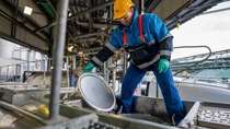 Das Foto zeigt eine Person, die in einer industriellen Anlage arbeitet und auf dem oberen Bereich eines Tankwagens steht. Das Foto zeigt eine Person, die in einer industriellen Anlage arbeitet und auf dem oberen Bereich eines Tankwagens steht.