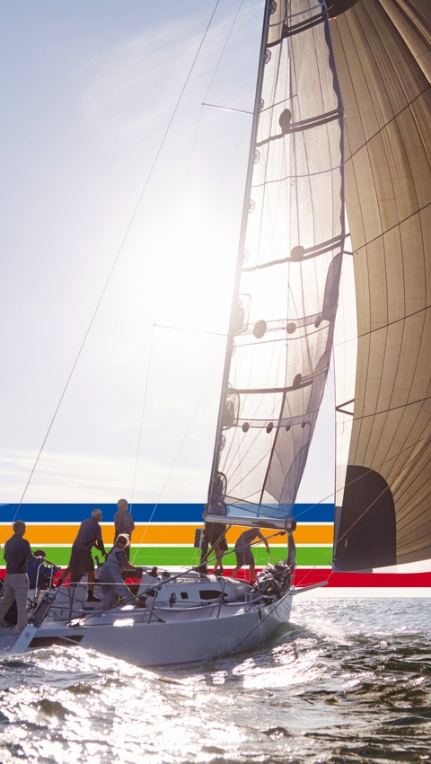 People on a sailing boat in the ocean, under a bright sky, surrounded by a key visual of four lines in blue, orange, green and red (photoshopped) People on a sailing boat in the ocean, under a bright sky, surrounded by a key visual of four lines in blue, orange, green and red (photoshopped)