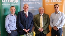 Four people, one holding a basket with flowers in it, standing in front of 3 BASF banners Four people, one holding a basket with flowers in it, standing in front of 3 BASF banners