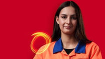 A BASF employee in an orange work jacket stands against a red background, looking at the camera, with glowing light trails beside her. A BASF employee in an orange work jacket stands against a red background, looking at the camera, with glowing light trails beside her.