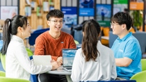 Vier junge chinesische Mitarbeitende sitzen an einem Besprechungstisch Vier junge chinesische Mitarbeitende sitzen an einem Besprechungstisch