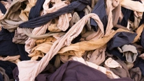 Gros plan sur une grande pile de pièces textiles usagées de différentes couleurs, emmêlées.  Gros plan sur une grande pile de pièces textiles usagées de différentes couleurs, emmêlées.