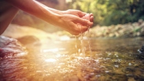 Human hand cupped to catch the fresh water from the river, reflection on water surface. Human hand cupped to catch the fresh water from the river, reflection on water surface.