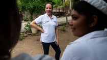 A woman with a BASF shirt posing in front of two otehr women. A woman with a BASF shirt posing in front of two otehr women.