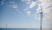 Close up of the rotor of a wind turbine, more wind turbines in the background standing in a calm sea Close up of the rotor of a wind turbine, more wind turbines in the background standing in a calm sea