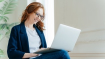 A business woman working with laptop on her lap.