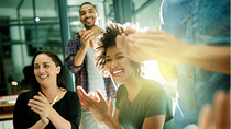 Eine fröhliche Gruppe von Kollegen applaudiert und lacht in einem modernen Büro, während Sonnenlicht durch die Fenster strahlt. Eine fröhliche Gruppe von Kollegen applaudiert und lacht in einem modernen Büro, während Sonnenlicht durch die Fenster strahlt.