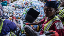 Three people sorting through a large pile of plastic bottles. Three people sorting through a large pile of plastic bottles.