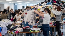 A group of people sorting through piles of clothing. A group of people sorting through piles of clothing.