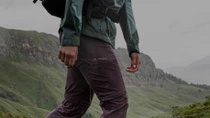 Gros plan sur la jambe d’un homme portant un pantalon Vaude gris, avec des montagnes en arrière-plan. Gros plan sur la jambe d’un homme portant un pantalon Vaude gris, avec des montagnes en arrière-plan.