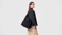 Un mannequin femme porte un sac à main noir sur l'épaule devant un fond neutre. Un mannequin femme porte un sac à main noir sur l'épaule devant un fond neutre.