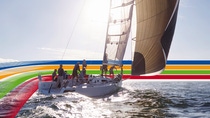 People on a sailing boat in the ocean, under a bright sky, surrounded by a key visual of four lines in blue, orange, green and red (photoshopped) People on a sailing boat in the ocean, under a bright sky, surrounded by a key visual of four lines in blue, orange, green and red (photoshopped)
