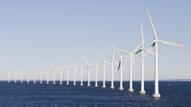 A row of white wind turbines stands in the ocean under a clear sky, generating renewable energy. A row of white wind turbines stands in the ocean under a clear sky, generating renewable energy.