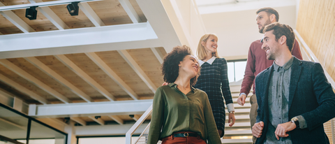 Four employees chatting while walking down the stairs Four employees chatting while walking down the stairs
