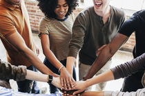 Eine diverse Gruppe von Menschen legt motiviert die Hände übereinander. Eine diverse Gruppe von Menschen legt motiviert die Hände übereinander.