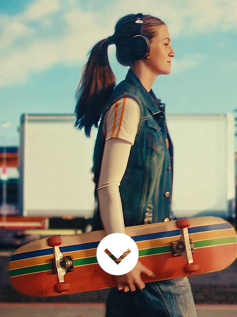 Une jeune femme portant un casque audio marche le long de la rue en tenant un skateboard. En arrière-plan, il y a des palmiers, des bâtiments et un camion. Un tourbillon lumineux apparaît sur la surface de la route. Une jeune femme portant un casque audio marche le long de la rue en tenant un skateboard. En arrière-plan, il y a des palmiers, des bâtiments et un camion. Un tourbillon lumineux apparaît sur la surface de la route.