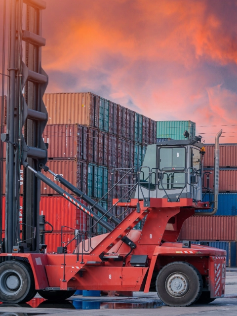 Crane lifting up container and unloading cargo into the import-export zone in yard.