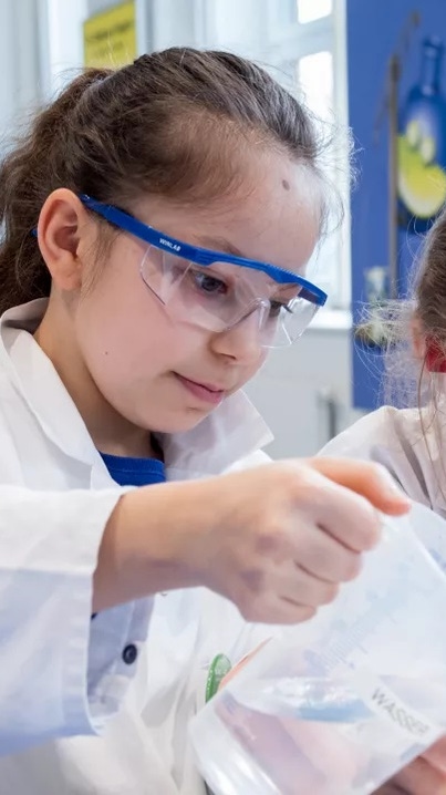 Zwei Kinder in Laborkitteln führen gemeinsam ein einfaches Experiment an einem Tisch durch. Zwei Kinder in Laborkitteln führen gemeinsam ein einfaches Experiment an einem Tisch durch.