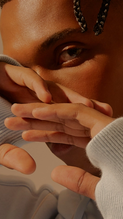 A man posing with his hands slightly in front of his face.