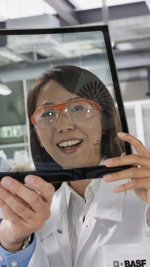 The project leader Miwa Sashida and the physicist Dr. Jochen Brill check a screen into which a transparent organic polymer film has been integrated. The latter reflects the infrared radiation and helps to keep the interior of the vehicle cool longer. The sheet developed by BASF SE combines maximum transparency in visible terms with efficient IR reflection.