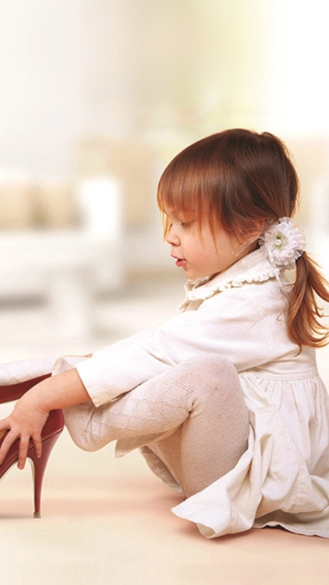 Cute little girl trying on red heels 