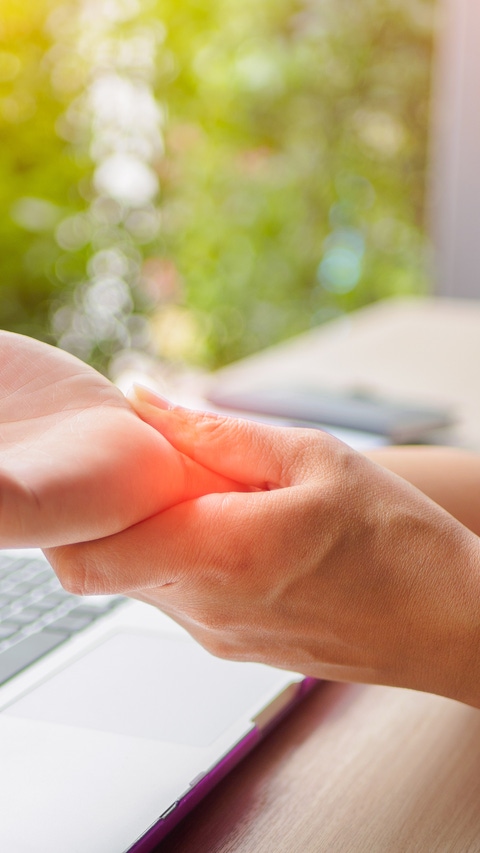 Closeup woman holding her painful hand from using computer. Office syndrome hand pain by occupational disease.