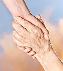 Two hands holding each other tightly, one younger and one older Two hands holding each other tightly, one younger and one older
