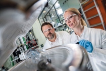Two scientists, one female and one male, wearing white lab coats in a laboratory researching new ways to recycle metals from EV batteries.  Two scientists, one female and one male, wearing white lab coats in a laboratory researching new ways to recycle metals from EV batteries.