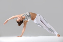 Young attractive woman practicing yoga, stretching in Bending Side Plank exercise, Vasisthasana pose, working out wearing sportswear, indoor full length, isolated against grey studio background Young attractive woman practicing yoga, stretching in Bending Side Plank exercise, Vasisthasana pose, working out wearing sportswear, indoor full length, isolated against grey studio background